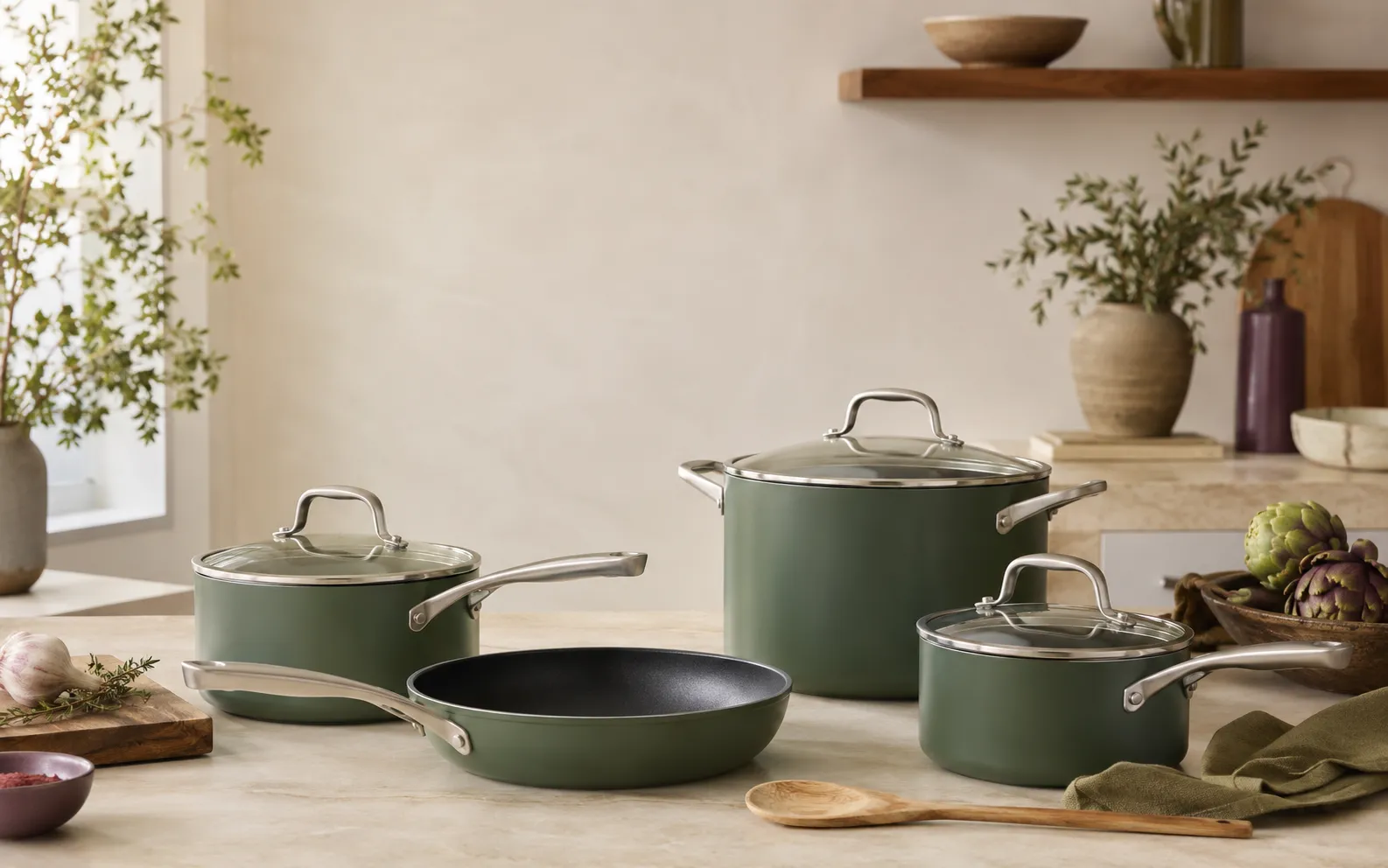 Cookware set arranged on a kitchen counter with skillets, saucepans, lids, and a stockpot